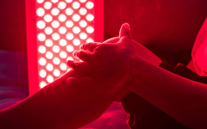 Closeup of a person treating a sore leg with the red light therapy panel