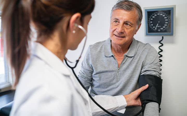Older man having BP checked at doctors office