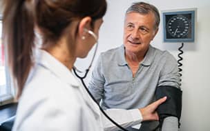 Older man having BP checked at doctors office