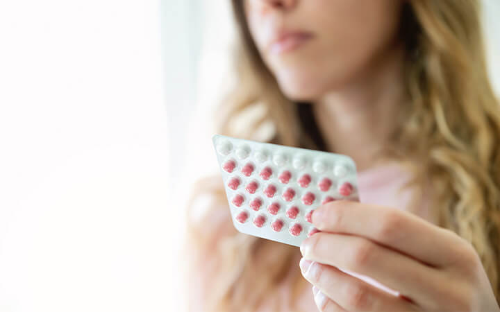 Close up of woman holding a sheet of contraceptive pills