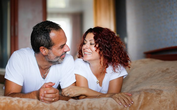 A middle aged couple together on their bed