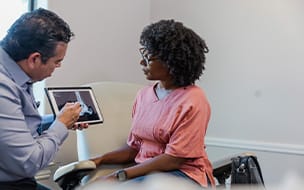A female patient sits with her podiatrist to review her x-ray and discuss new treatment options