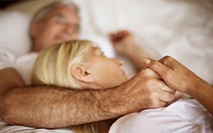 A mature couple embracing in bed