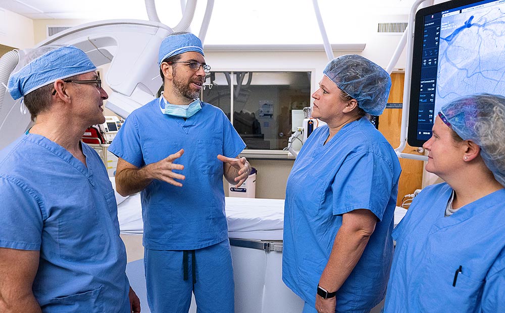 Luis Augusto Palma Dallan, MD, PhD discusses a heart procedure with his colleagues