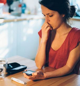 Getty image of woman looking worried as she looks at glucose results
