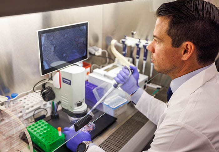Tyler Miller, MD workign at lab bench with CART T cells.