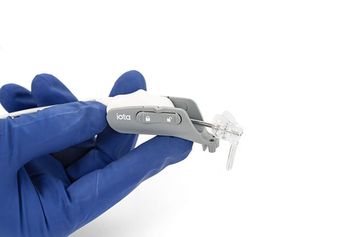Blue gloved hand holding Iotamotion iotasoft cochlear implant device.