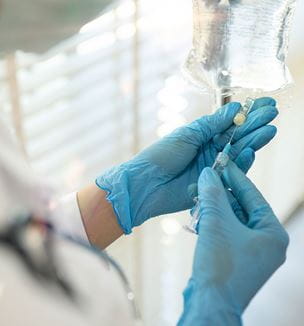 Hands with blue gloves are preparing infusion IV drip