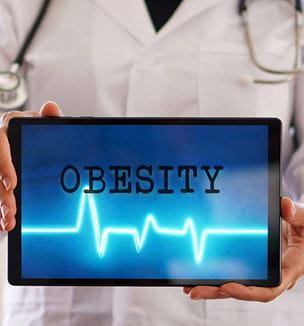 Doctor holding ipad with word obesity and heart rhythm displayed.