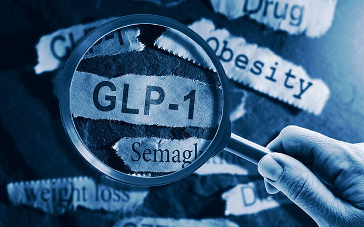 GLP-1 related drugs newspaper headlines with hand and magnifying glass.