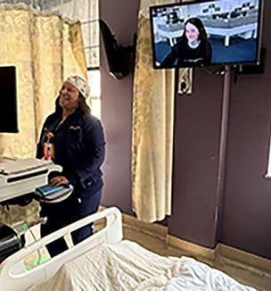 Nurse talking to another nurse on tv showing virtual nursing interaction in a pediatric patient room.