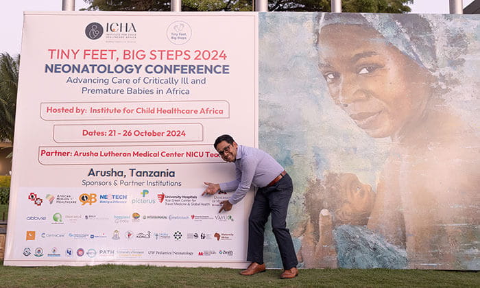 Samudragupta Bora, PhD in front of large logo sign at the Tiny Feet Big Steps conference.
