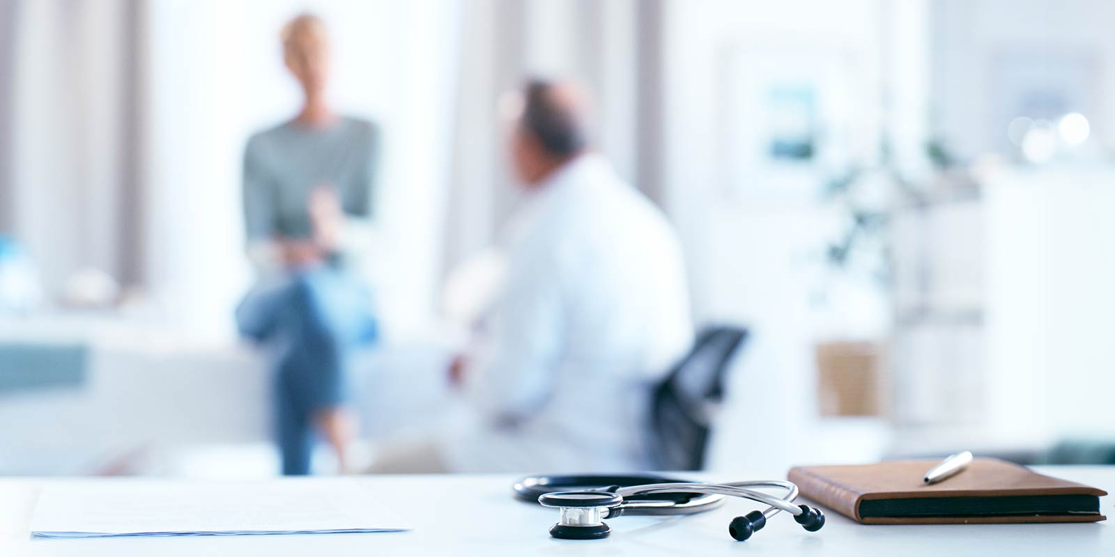 Blur background with close-up of a stethoscope and notebook with pen