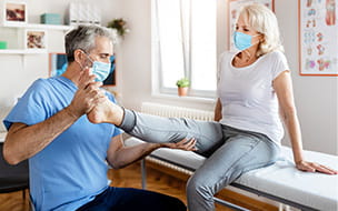 Physiotherapist Massaging Leg of Senior Woman for bladder control therapy
