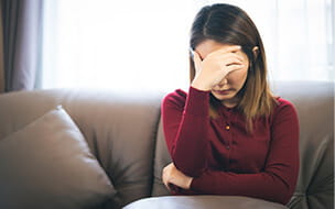 Depressed woman sitting on sofa during coronavirus outbreak