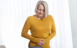 Middle aged woman suffering from abdominal pain while at home