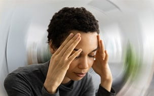 African American woman holding her head with both hands due to head pain.