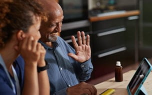 Smiling senior man waving at doctor on video call through digital tablet at home