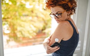 Patient waving a reader device over sensor to see the current blood sugar level