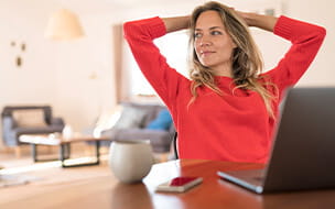 Woman sitting at dining table at home having a break from her work at the laptop