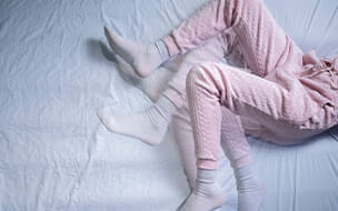 Woman moving in bed with Restless Legs Syndrome (RLS)