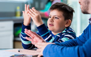 Hispanic boy uses his fingers on math problem with his father