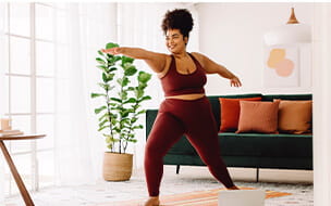 Woman in sports wear watching online video on laptop doing yoga at home