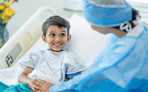 A female doctor checks in on a young male patient after his surgery.