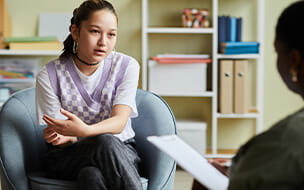 Teenage girl talking to psychologist during consultation at office