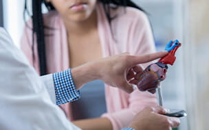 African American teenage girl listens as a doctor points to something on a model of the human heart.