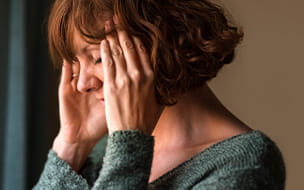 Close-up shot of a woman suffering from a headache and rubbing her temples