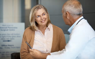 Smiling senior woman listening to male doctor in hospital