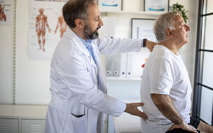 Physical therapist examining senior patient's back injury at doctor's office