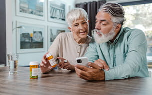 Senior couple holding bottles with pills and a cell phone to research them