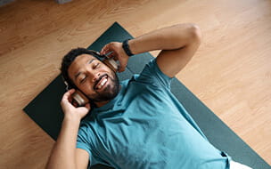 Man exercising at home while listening to music through wireless headphones