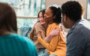 Teenagers hugging in group therapy