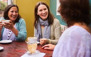 Women talking and having coffee at an outside table