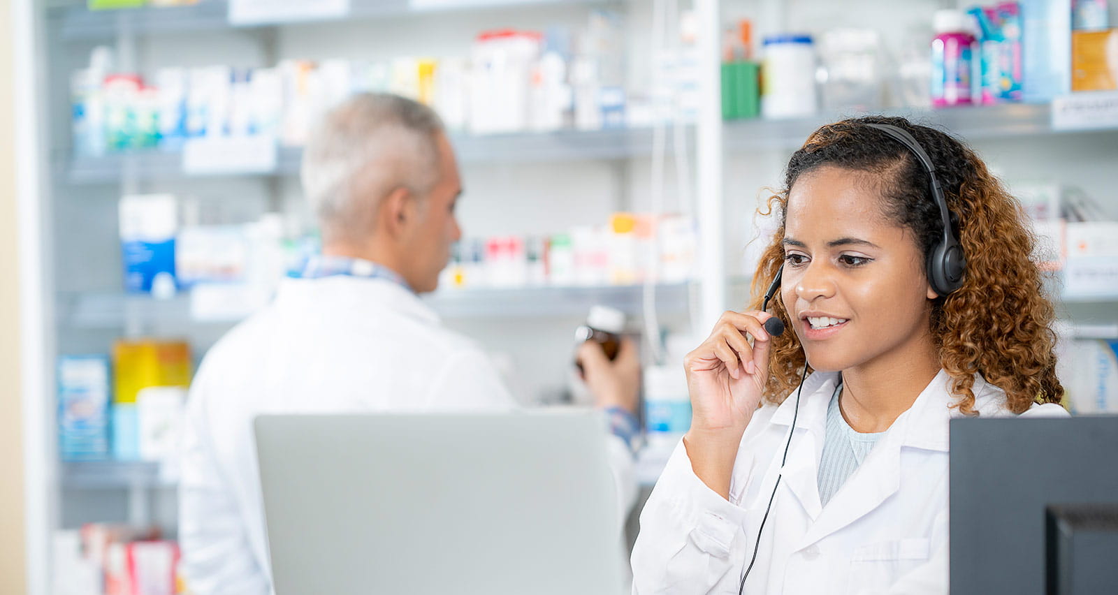 A female pharmacist uses a computer at the counter of a retail pharmacy