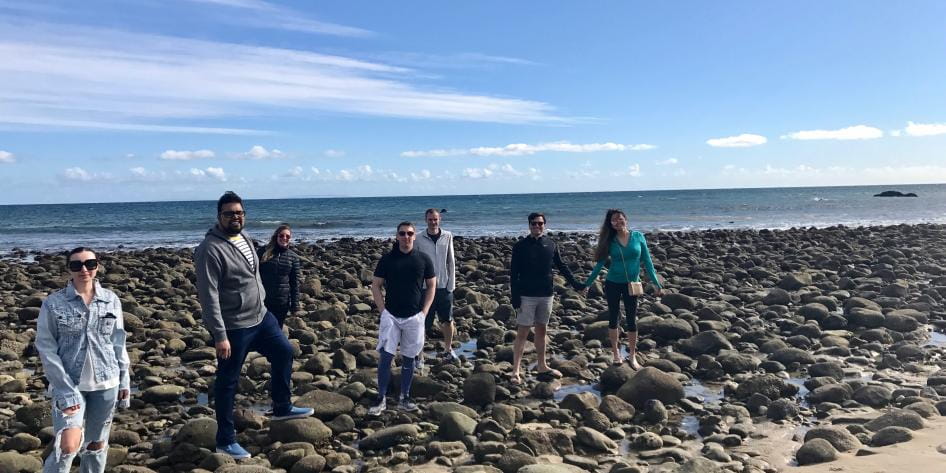 Group photo of residents standing on beach with blue sky background