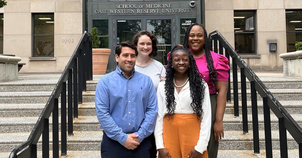 graduates posing on steps to building