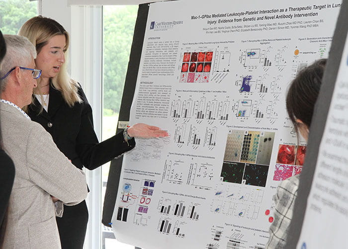 Dan Simon, MD looks at poster with poster presenter.