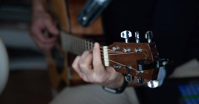 close up of hands playing a guitar