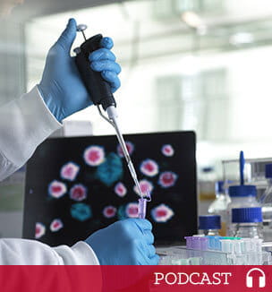 scientist with pipette in front of laptop
