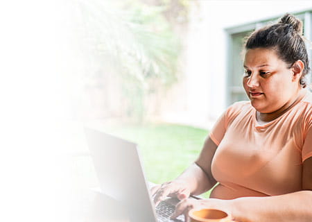 An adult woman browsing on a laptop on her patio