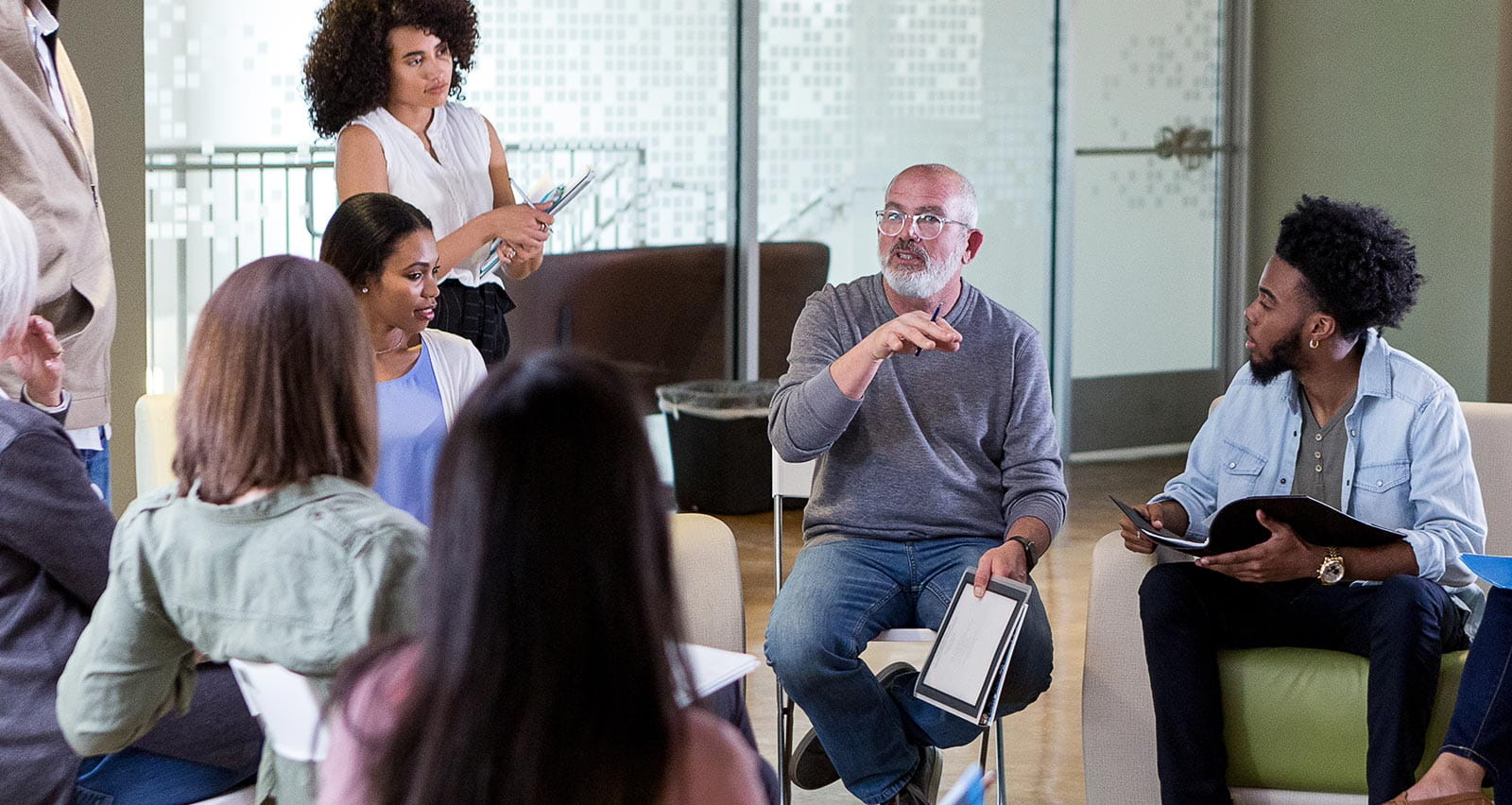 A mature adult has a discussion with a group at a community center
