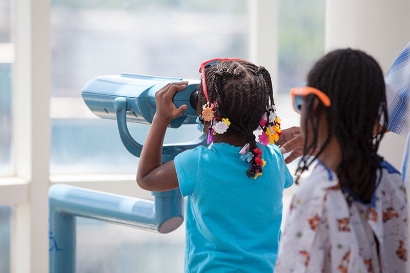 Two girls watching the butterfly release in Angies' Garden at Rainbow Babies & Children’s Hospital