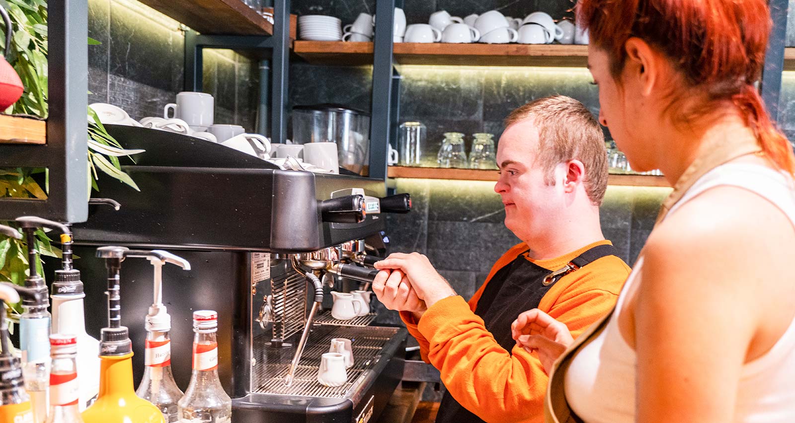 A young man with Down Syndrome working at a cafe, preparing coffee