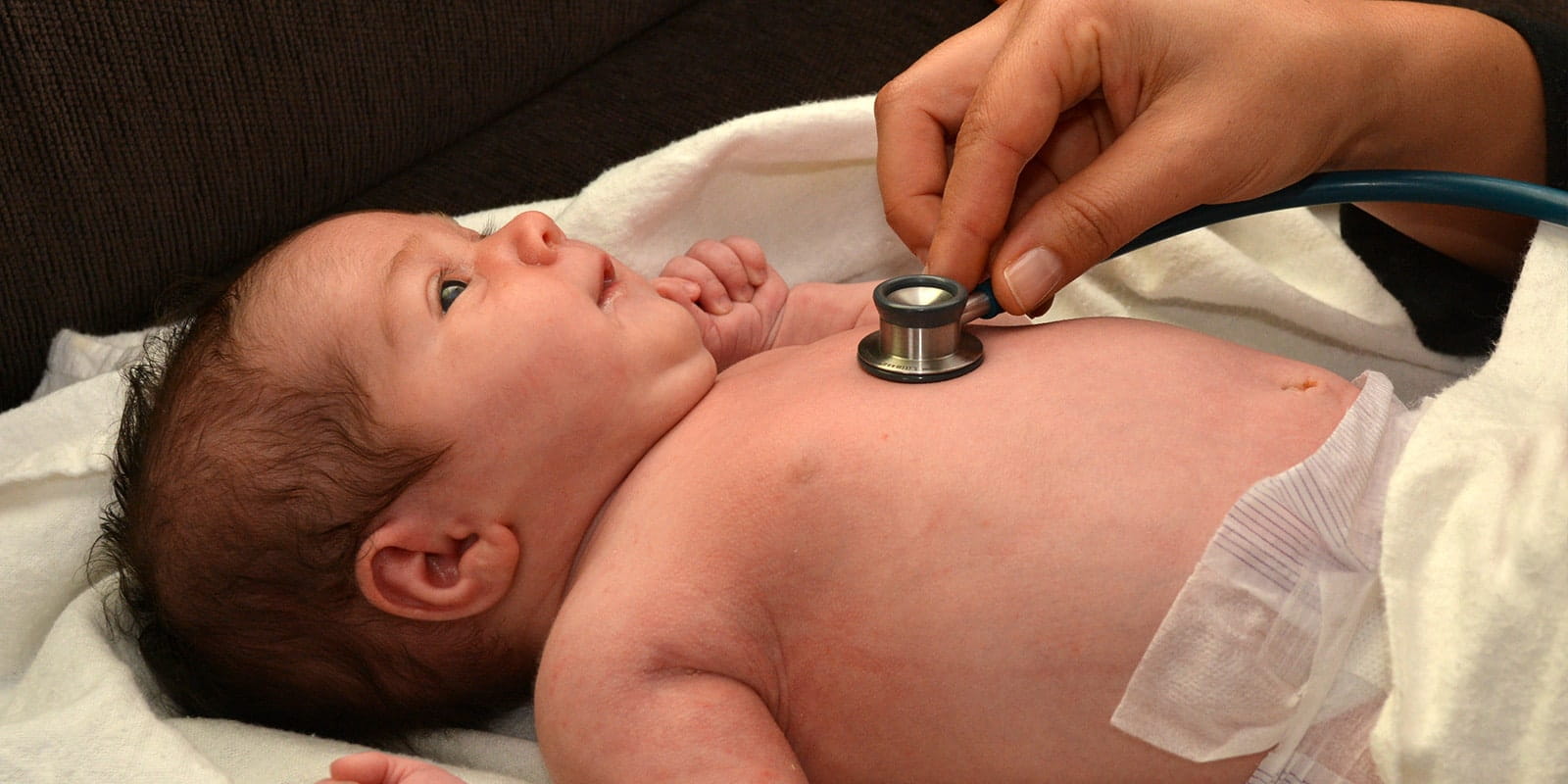 Doctor listening to baby's heartbeat using stethoscope.