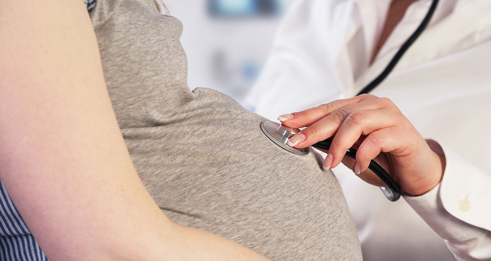 A doctor listening to a pregnant woman's baby