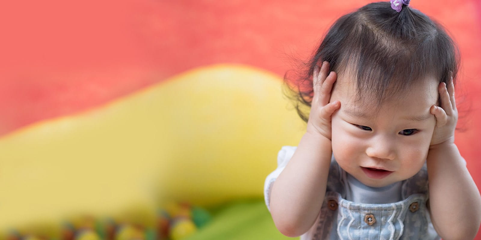 Little girl holding head in playroom.